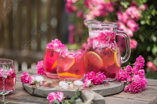 Fresh Rose lemonade or cokctail  with ice and fresh roses over natural garden