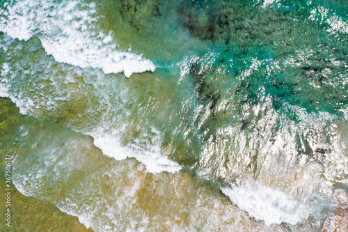 Beach, beautiful waves, blue water at sunrise. Top view from drone.
