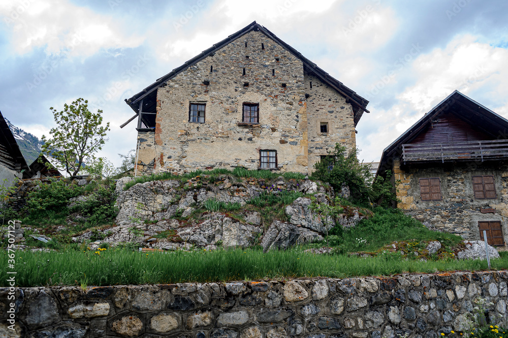 View of a typical house of the Hautes-Alpes. The stone of the country has grey tints and is covered with lime in places. The house is built on a boulder.