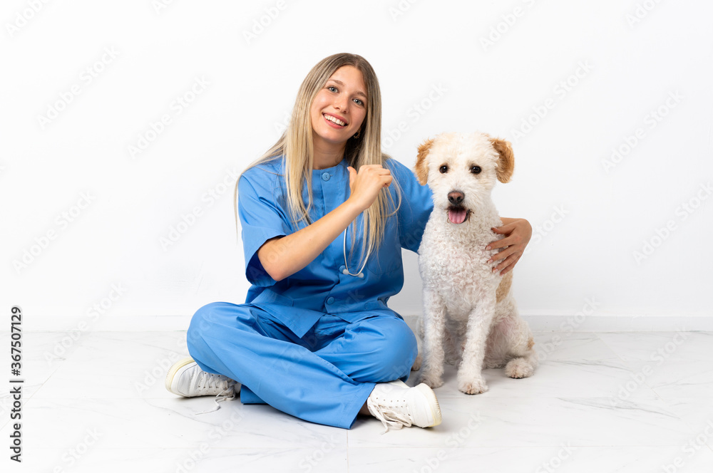 Young veterinarian woman with dog sitting on the floor proud and self-satisfied Young veterinarian woman with dog sitting on the floor proud and self-satisfied