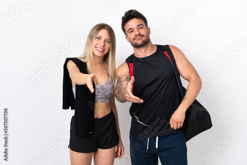 Young sport couple isolated on white background shaking hands for closing a good deal