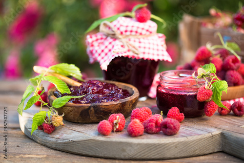 Fresh raspberries jam with fresh raspberries on natural garden. Selective focus