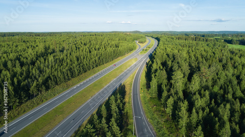 Aerial view of unlimited space of forest plain and cars which are riding on highway.