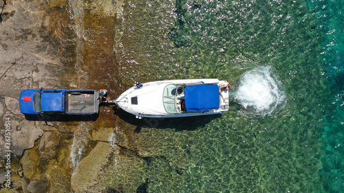 Aerial top view photo of inflatable speed boat on trailer being towed by truck from emerald exotic sea to land