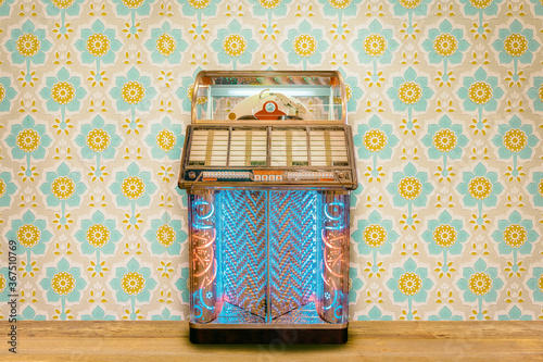 Bild auf Leinwand Colorful vintage jukebox in front of retro flower wallpaper