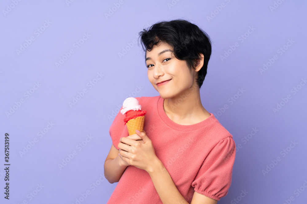 Young Vietnamese woman with short hair holding a cornet ice cream over isolated purple background Young Vietnamese woman with short hair holding a cornet ice cream over isolated purple background
