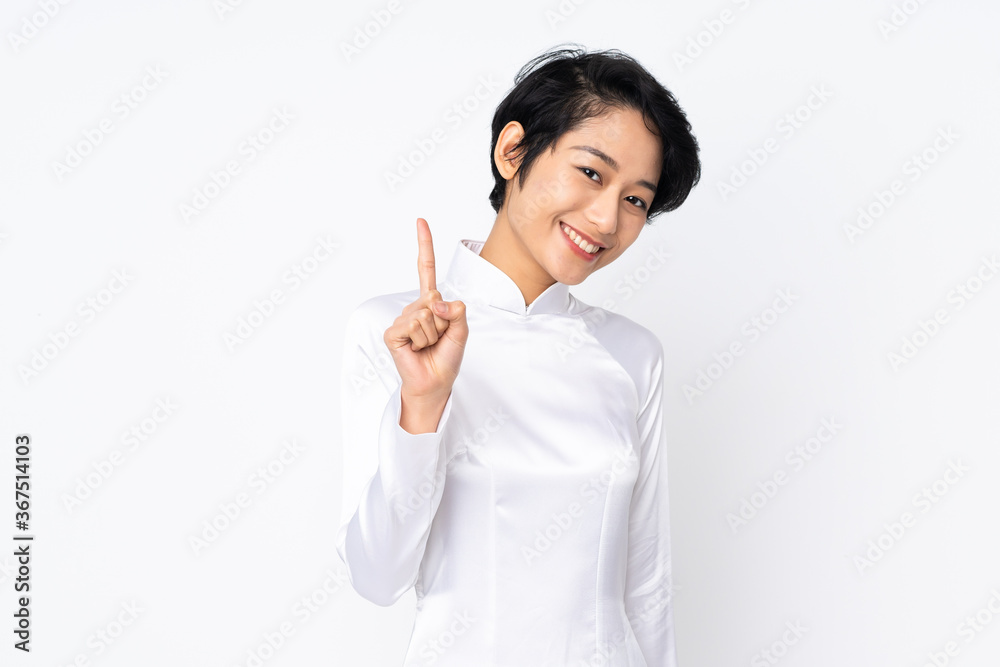 Young Vietnamese woman with short hair wearing a traditional dress over isolated white background showing and lifting a finger in sign of the best Young Vietnamese woman with short hair wearing a traditional dress over isolated white background showing and lifting a finger in sign of the best