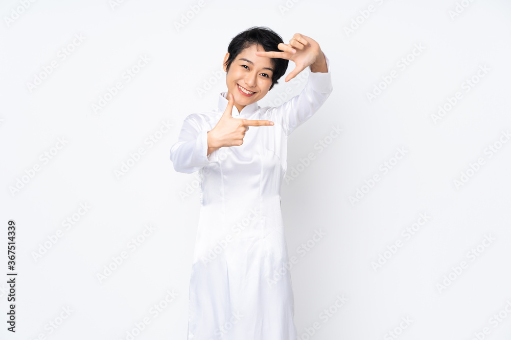 Young Vietnamese woman with short hair wearing a traditional dress over isolated white background focusing face. Framing symbol Young Vietnamese woman with short hair wearing a traditional dress over isolated white background focusing face. Framing symbol