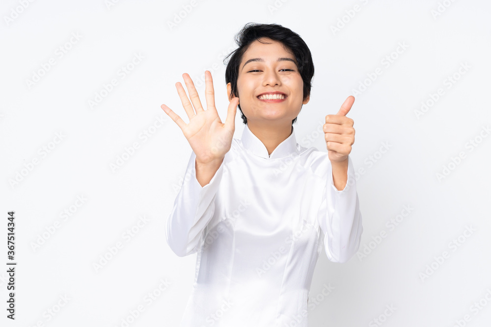 Young Vietnamese woman with short hair wearing a traditional dress over isolated white background counting six with fingers Young Vietnamese woman with short hair wearing a traditional dress over isolated white background counting six with fingers