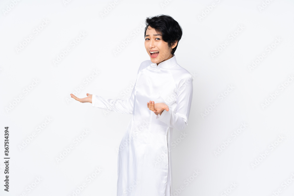 Young Vietnamese woman with short hair wearing a traditional dress over isolated white background with surprise expression while looking side Young Vietnamese woman with short hair wearing a traditional dress over isolated white background with surprise expression while looking side