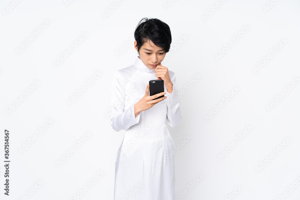 Young Vietnamese woman with short hair wearing a traditional dress over isolated white background thinking and sending a message Young Vietnamese woman with short hair wearing a traditional dress over isolated white background thinking and sending a message