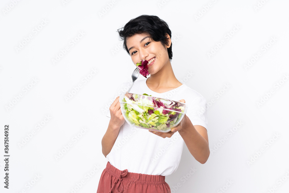 Young Vietnamese woman with short hair holding a salad over isolated background Young Vietnamese woman with short hair holding a salad over isolated background