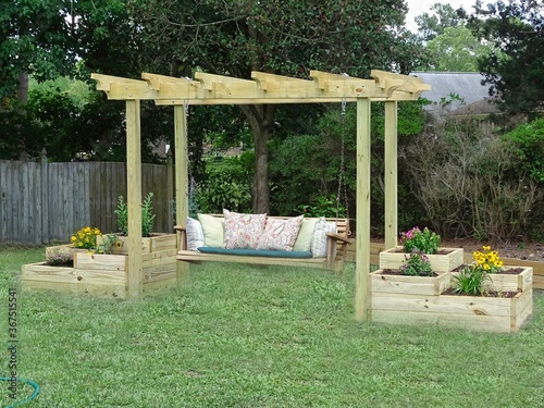 Outdoor wooden swing hanging from a trellis