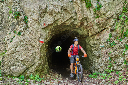 a man on a mountain bike coming out of a tunnel from the stone
