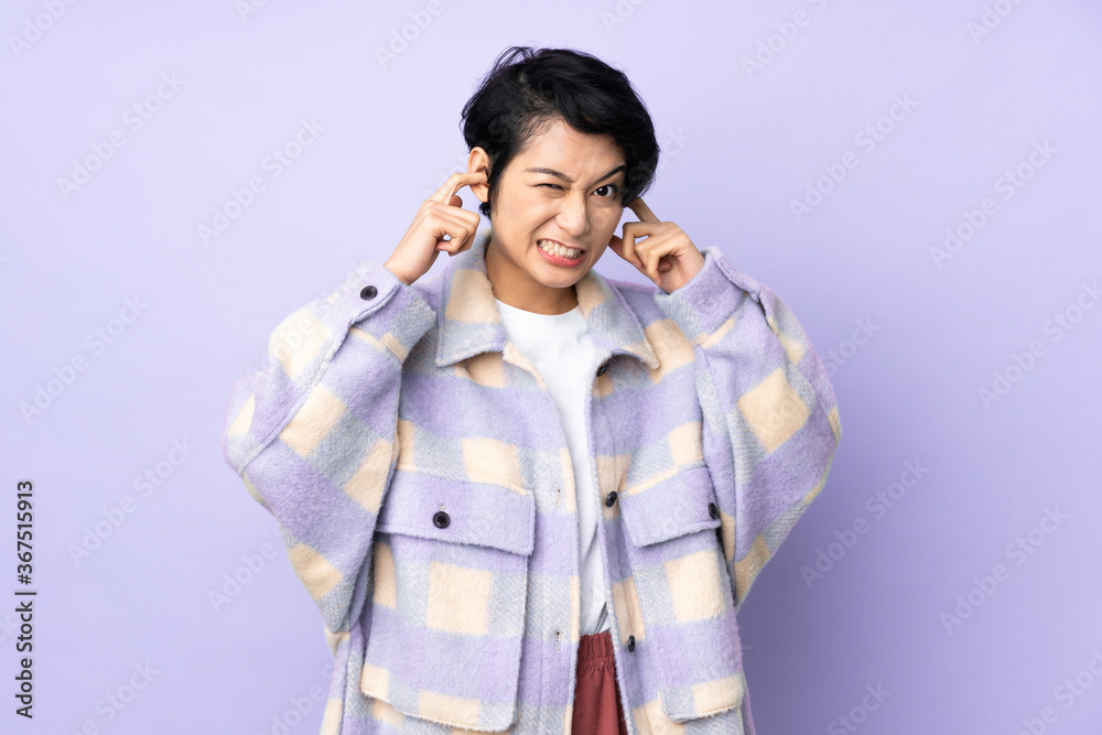 Young Vietnamese woman with short hair over isolated background frustrated and covering ears Young Vietnamese woman with short hair over isolated background frustrated and covering ears