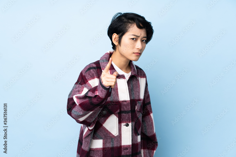 Young Vietnamese woman with short hair over isolated background frustrated and pointing to the front Young Vietnamese woman with short hair over isolated background frustrated and pointing to the front