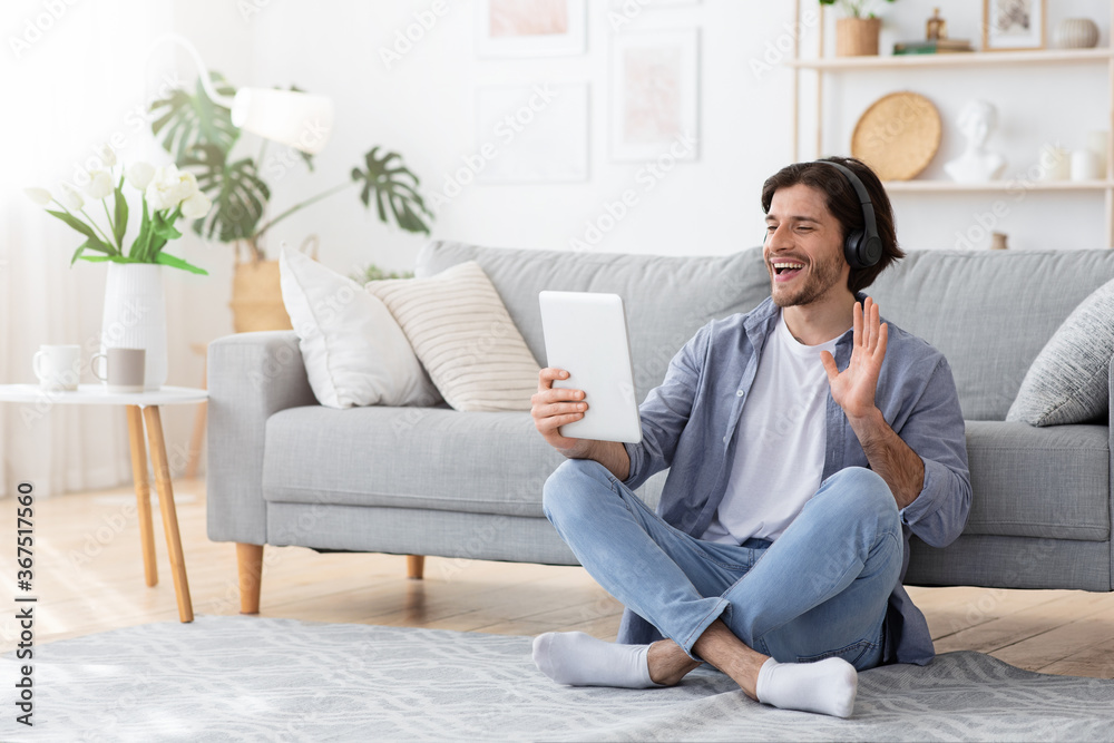 Positive guy having videocall, using digital tablet at home Positive guy having videocall, using digital tablet at home