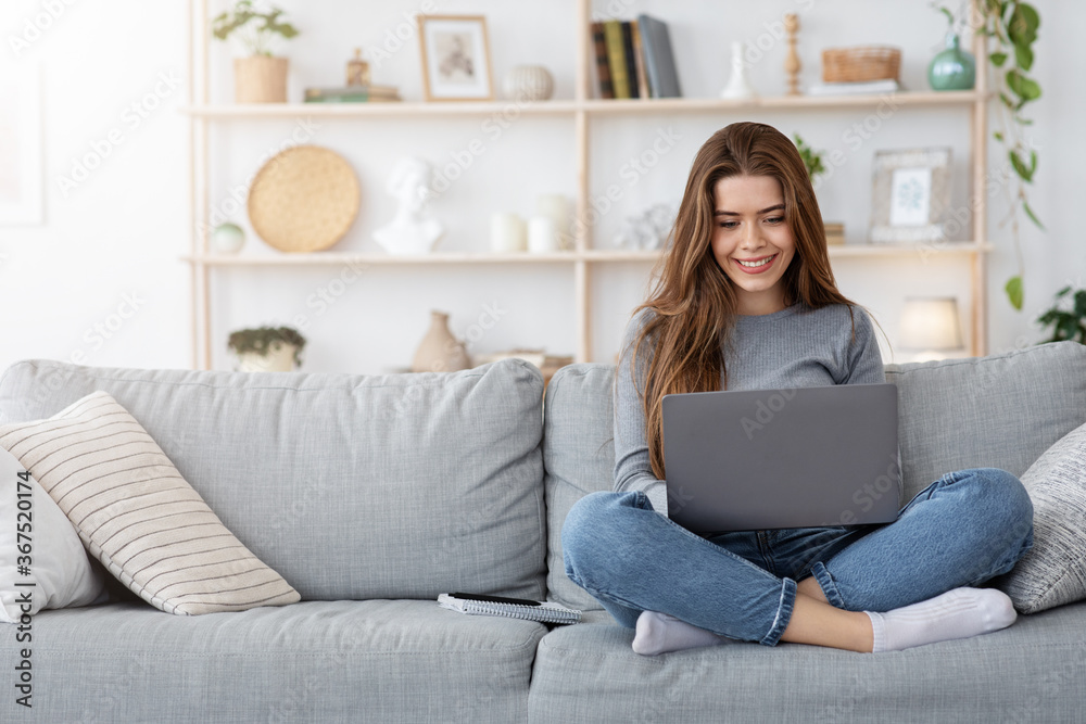 Smiling young woman working from home, using laptop Smiling young woman working from home, using laptop