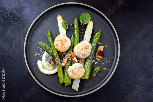 Traditional barbecue scallops with green and white asparagus offered as top view on a modern design plate with copy space
