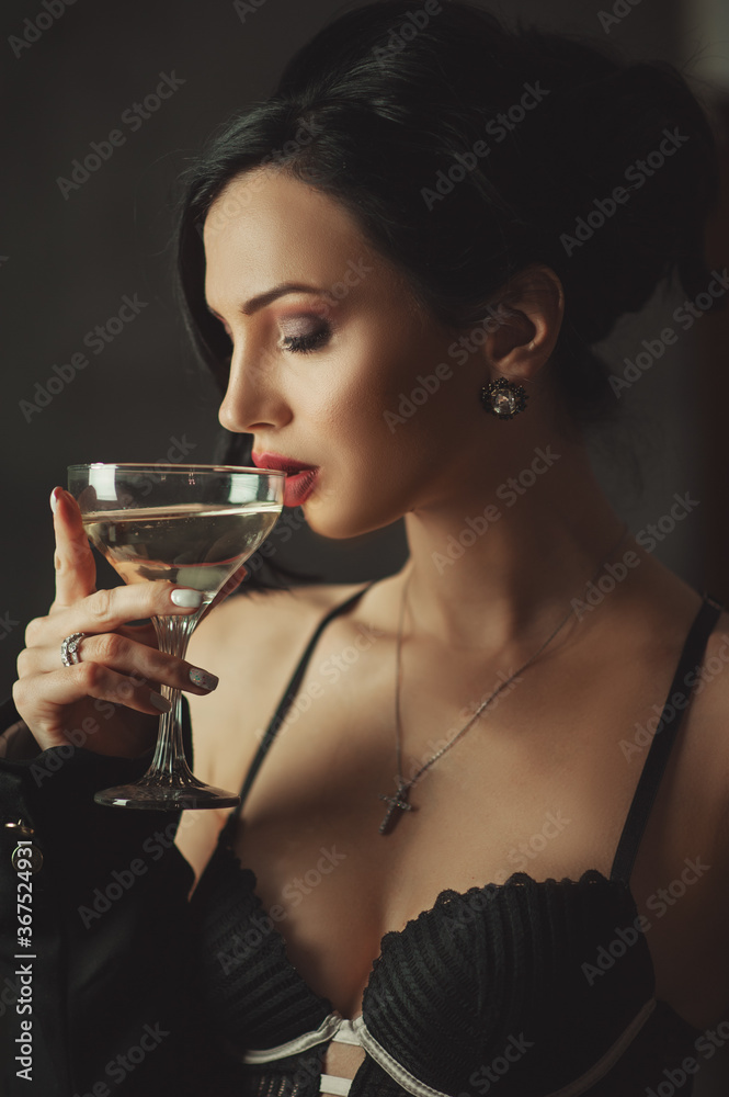 Fashion model in lingerie with wavy hairstyle holding glass of champagne. Attractive young girl with curly hair posing at studio. Face of a beautiful woman with long brown curly hair. Fashion model in lingerie with wavy hairstyle holding glass of champagne. Attractive young girl with curly hair posing at studio. Face of a beautiful woman with long brown curly hair.
