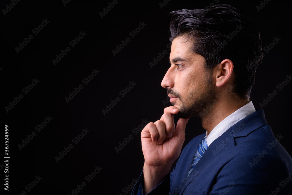 Young handsome bearded Persian businessman against black background Young handsome bearded Persian businessman against black background