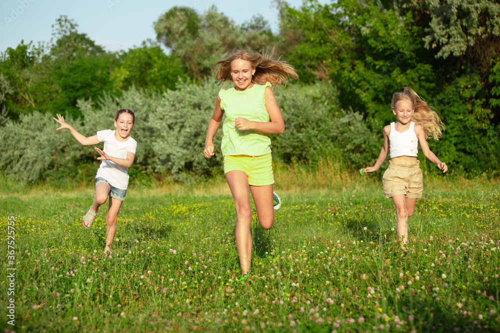 Kids, children running on meadow in summer's sunlight. Look happy, cheerful with sincere bright emotions. Cute caucasian boys and girls. Concept of childhood, happiness, movement, family and summer. Kids, children running on meadow in summer's sunlight. Look happy, cheerful with sincere bright emotions. Cute caucasian boys and girls. Concept of childhood, happiness, movement, family and summer.