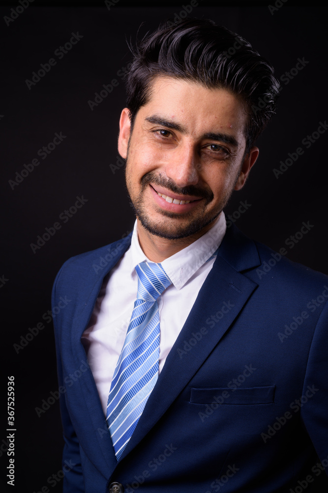 Young handsome bearded Persian businessman against black background Young handsome bearded Persian businessman against black background