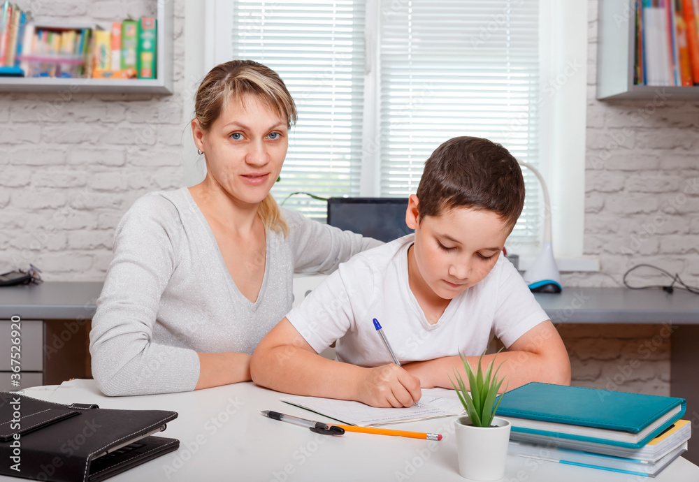 Schoolboy doing homework at home with school books and digital pad Schoolboy doing homework at home with school books and digital pad