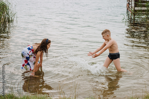Boy and girl playing in the water on a lake shore. Summer Holidays