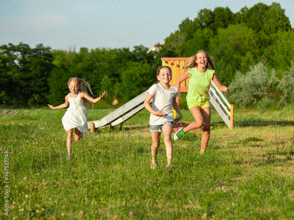 Kids, children running on meadow in summer's sunlight. Look happy, cheerful with sincere bright emotions. Cute caucasian boys and girls. Concept of childhood, happiness, movement, family and summer. Kids, children running on meadow in summer's sunlight. Look happy, cheerful with sincere bright emotions. Cute caucasian boys and girls. Concept of childhood, happiness, movement, family and summer.
