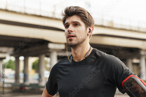 Image of athletic caucasian sportsman using earphones while working out © Drobot Dean
