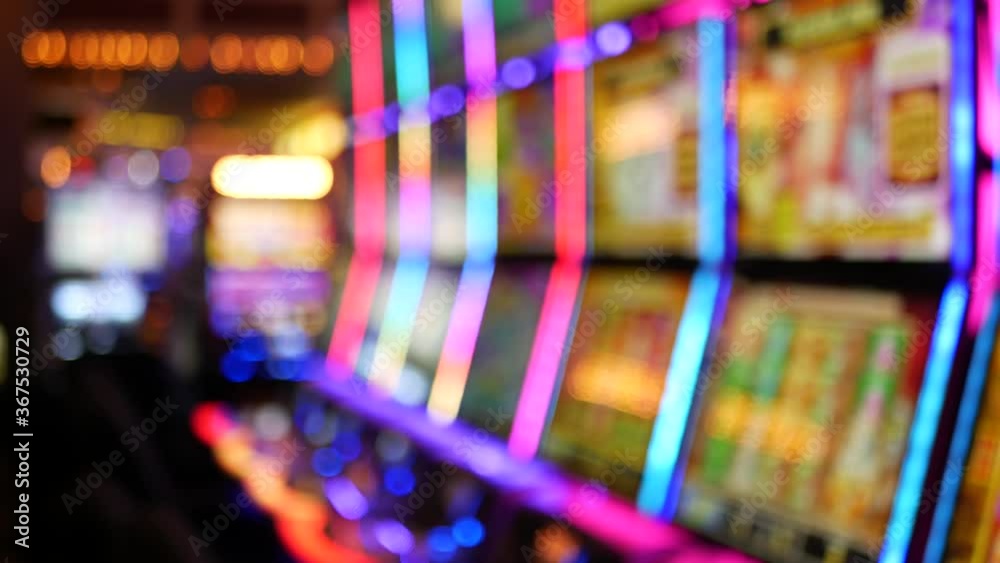 Defocused slot machines glow in casino on fabulous Las Vegas Strip, USA. Blurred gambling jackpot slots in hotel near Fremont street. Illuminated neon fruit machine for risk money playing and betting.