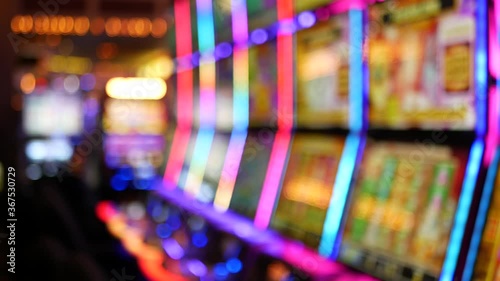 Defocused slot machines glow in casino on fabulous Las Vegas Strip, USA. Blurred gambling jackpot slots in hotel near Fremont street. Illuminated neon fruit machine for risk money playing and betting.