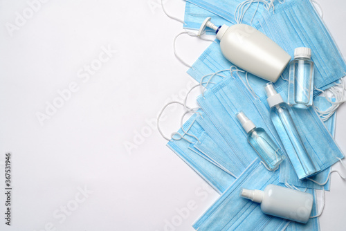 bottle of lotion, sanitizer or liquid soap and protective mask over light grey background