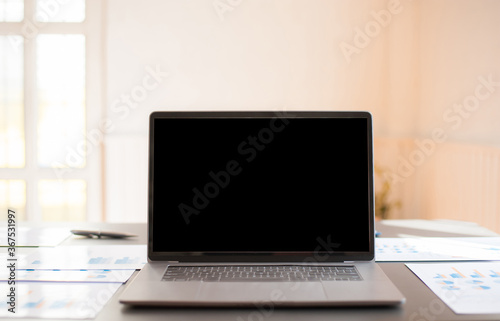 A laptop with an empty screen on an office desk.