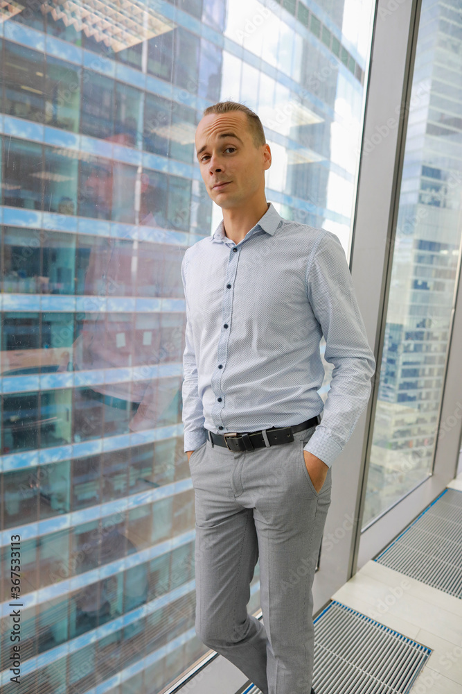 a young man stands at the window in the office a young man stands at the window in the office