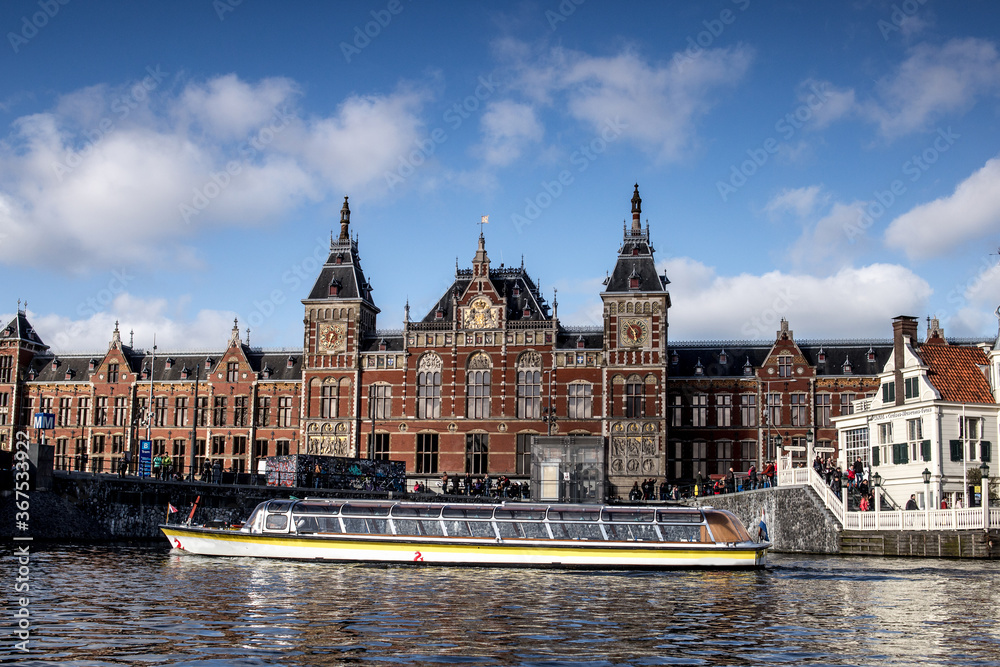 Ámsterdam Central desde el canal con un barco turístico