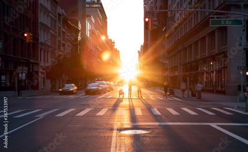 People standing in the middle of the intersection at 23rd Street in New York City taking pictures of the summer sunset