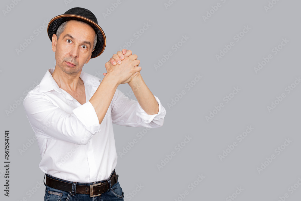 Portrait of attractive man in hat and white shirt. Man shows gesture of consent with his hands. Isolated grey background. Body language concept. Copy space Portrait of attractive man in hat and white shirt. Man shows gesture of consent with his hands. Isolated grey background. Body language concept. Copy space