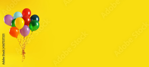 Photography Bunch of bright balloons on yellow background, space for text