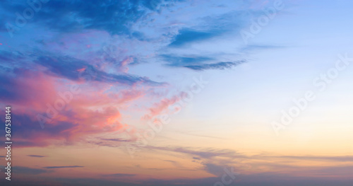 Dramatic colorful sunset blue sky with clouds. Bright orange and pink sunlight reflects on a fluffy cloud. Beautiful mystical twilight or dawn background. Banner with copy space.