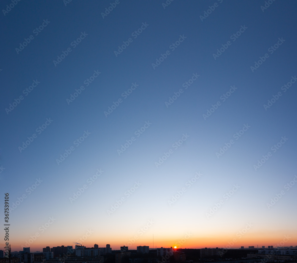 Panorama of sunset, clear blue sky and sun over city.