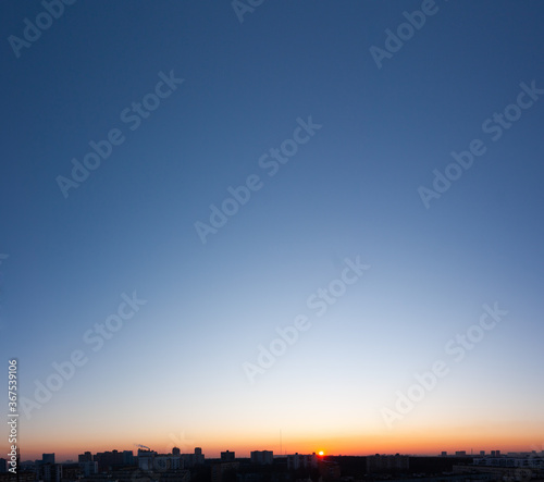 Panorama of sunset, clear blue sky and sun over city.