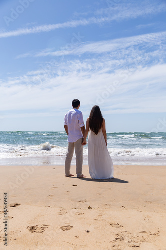 couple on the beach on a background of sea and blue sky with clouds