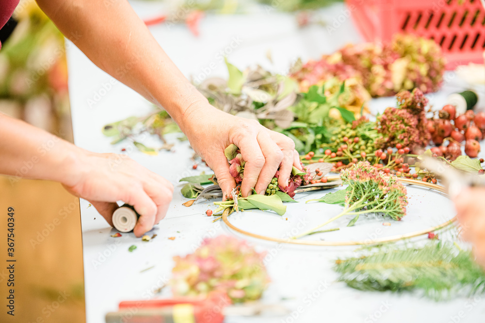 Florist at work: woman making rose hip and hawthorn wreath