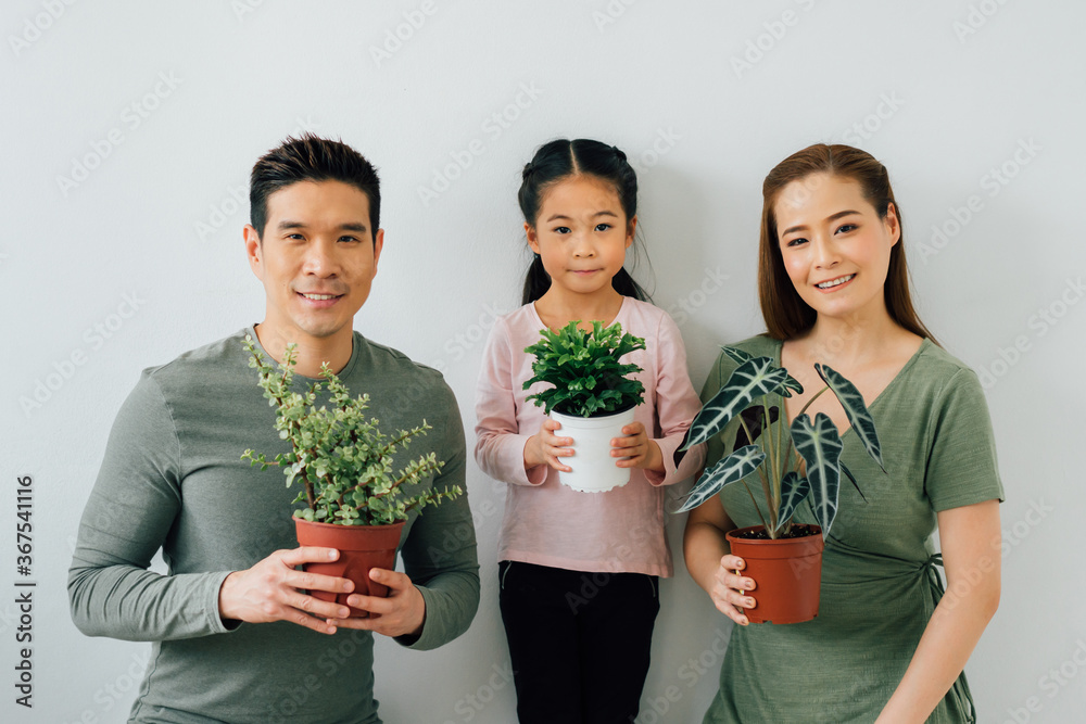 Chinese mother and father looking at camera with young daughter holding plants Chinese mother and father looking at camera with young daughter holding plants