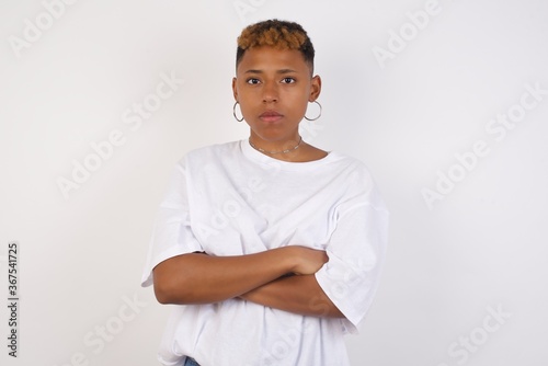 Picture of angry young beautiful woman standing isolated over bright background. Looking camera.