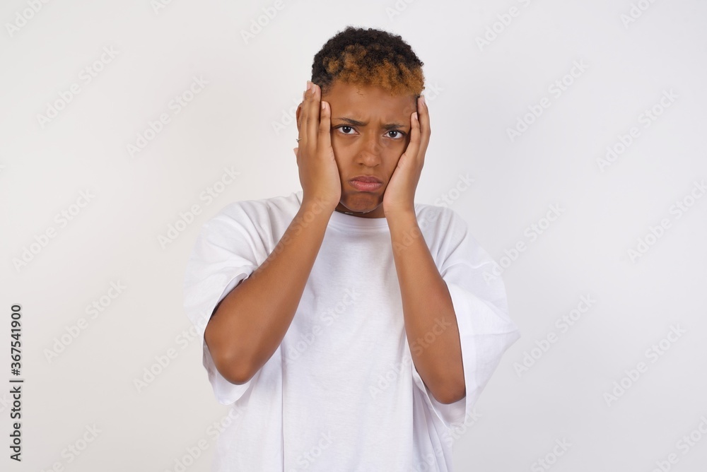 Portrait of beautiful young woman holding head in hands with unhappy expression watching sad movie about animals and trying not to cry. Portrait of beautiful young woman holding head in hands with unhappy expression watching sad movie about animals and trying not to cry.