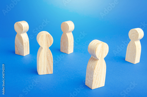 Wooden figurines of people stand on a blue background. Loneliness and disconnection. Safe spacing between persons, new normal. Faceless mass. Communication. Society public. Disunity concept.