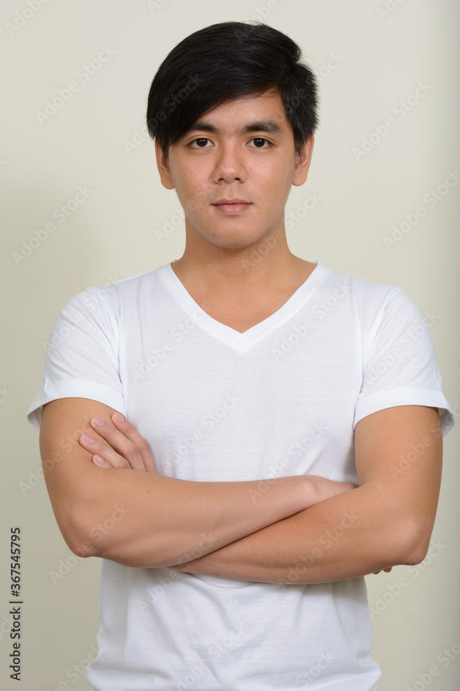 Obraz premium Portrait of young handsome Asian man against white background